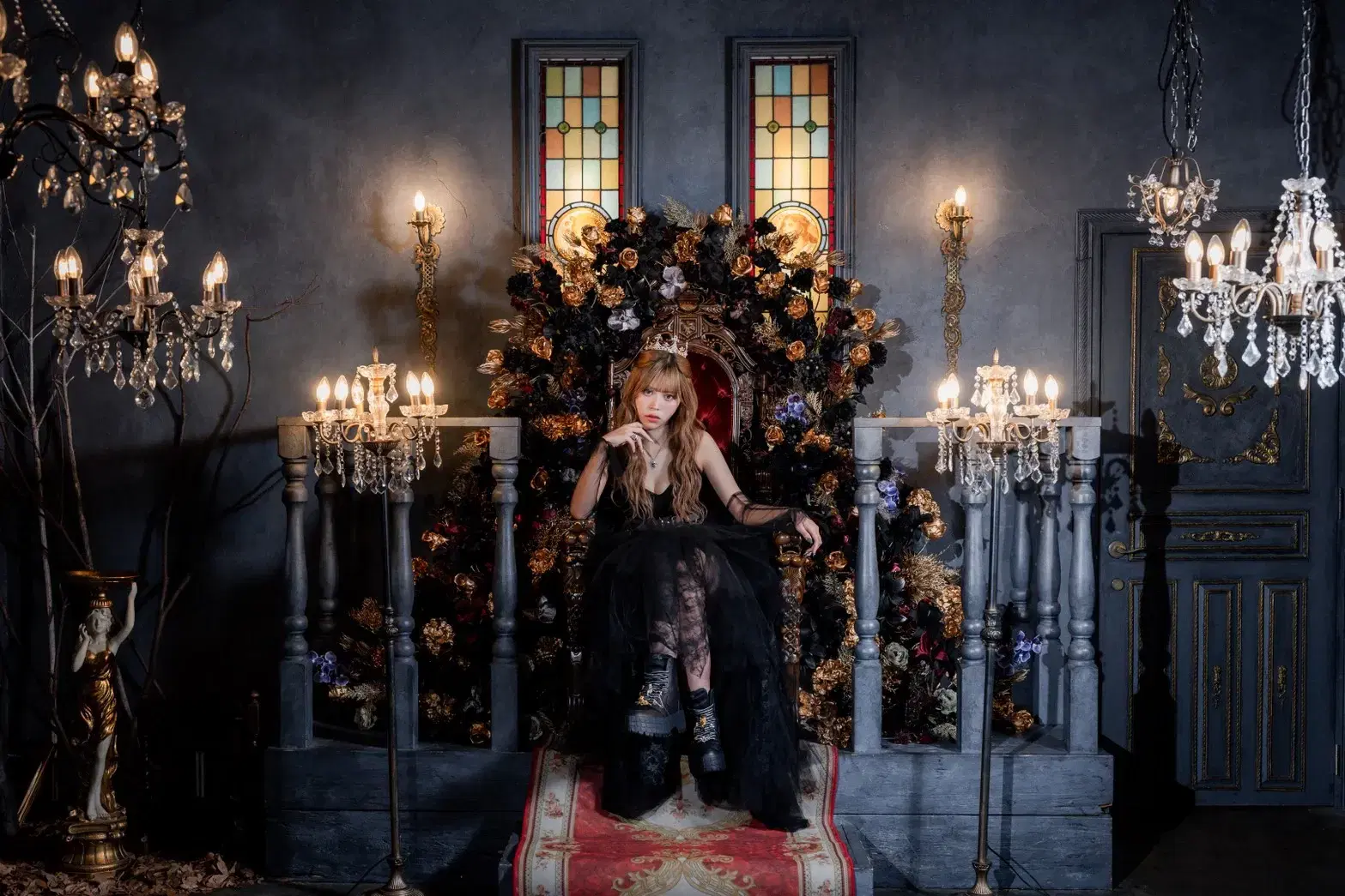 ブラックドレスを纏いペコラのジュエリーを身に着けた女性が、女王のように神秘的に玉座に座る姿