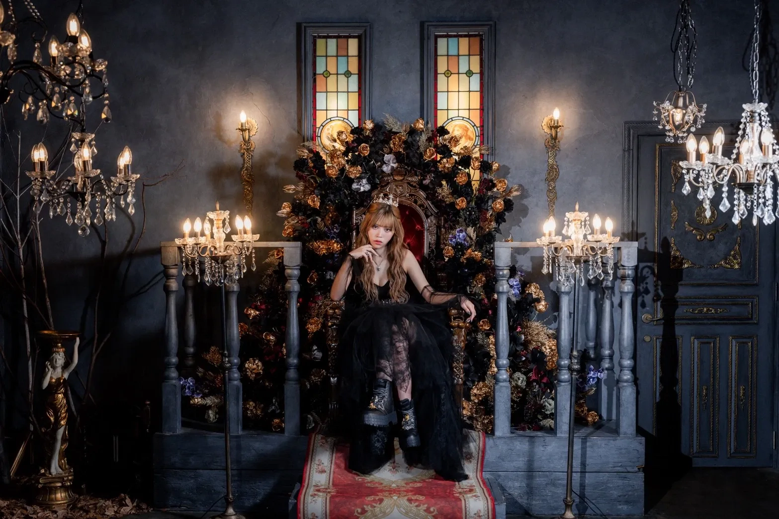 ブラックドレスを纏いペコラのジュエリーを身に着けた女性が、女王のように神秘的に玉座に座る姿
